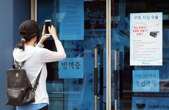 11일 오후 서울 양천구 메디힐병원 입구에서 한 내원객이 출입통제에 대한 병원 안내문을 스마트폰으로 촬영하고 있다. 서울시는 이날 시장-구청장 연석회의를 열고 메르스에 감염된 98번 환자가 입원했던 양천구 메디힐병원에 대해 23일까지 입·퇴원을 금지하는 등 영업중단 조치했다. 98번 환자는 전염력이 가장 왕성할 때인 6월 4일부터 3일간 메디힐병원에 입원했다.
